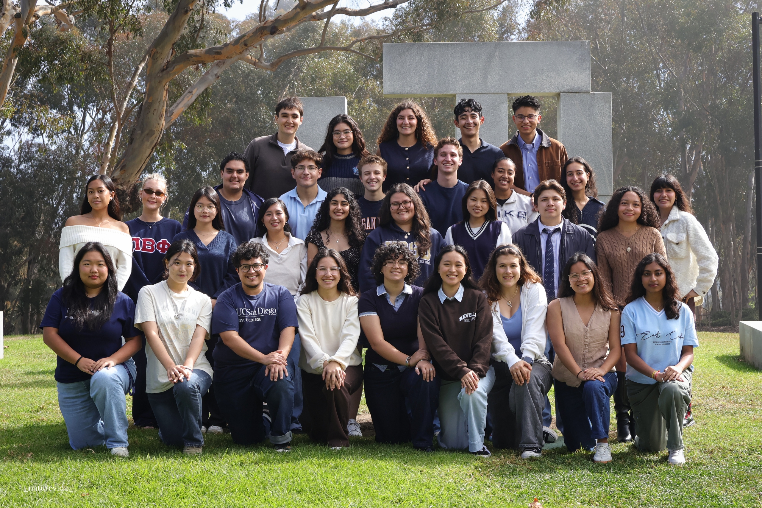 Revelle College Council members stand and kneel in rows in front of the Stonehenge Art piece in Revelle.